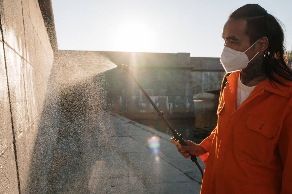Pest control technician treating the exterior wall of a home